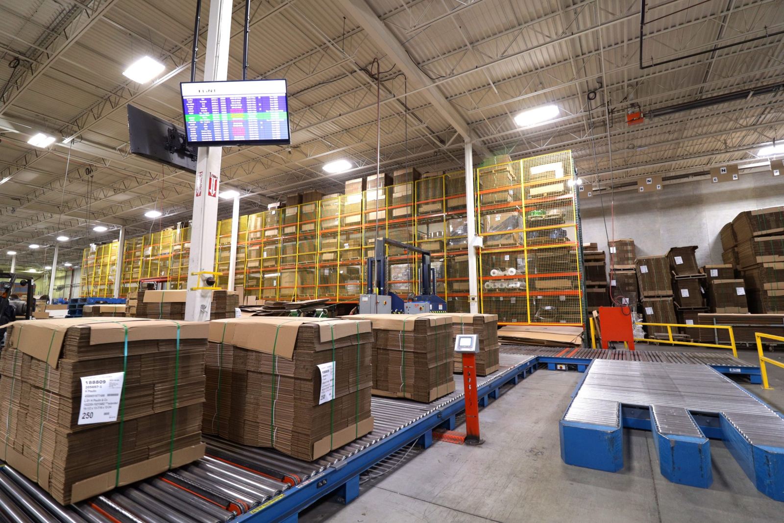Stacks of corrugated sheets on conveyors inside the Flint Packaging plant