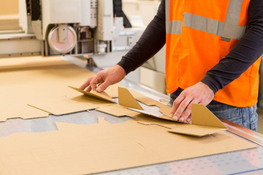 A worker folding a prototype box from a printed sheet